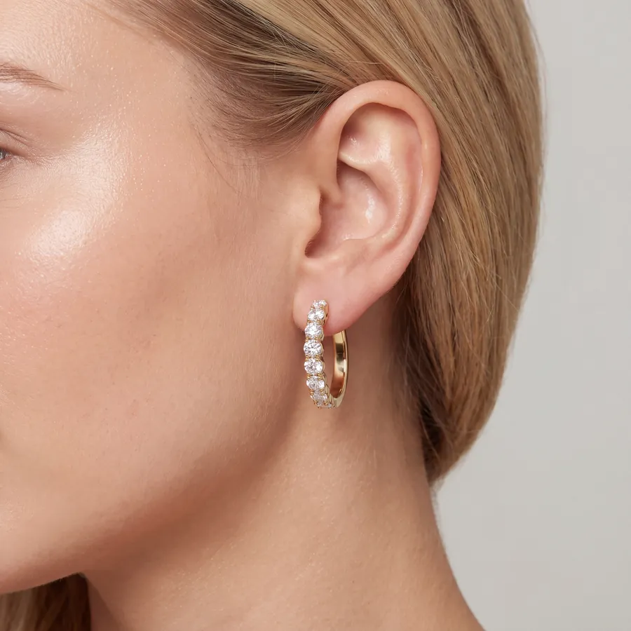 Diamond huggie hoop earring in yellow gold worn on the ear